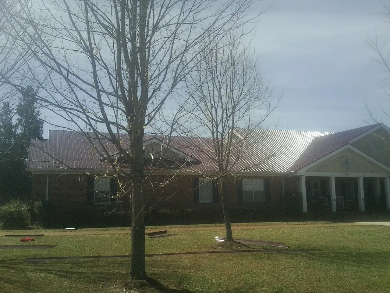 Red metal roof on a brick building seen from the front lawn in Harper Woods
