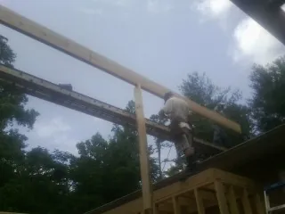 Carpenter setting a ridge beam over a new addition frame — Ice Dam Removal by Roofing Brothers in Harper Woods