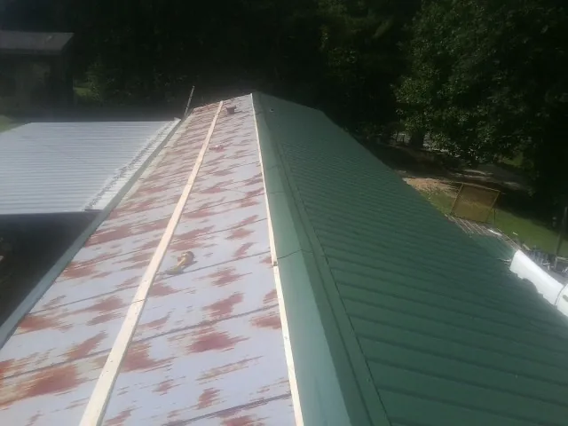Old rusted panels beside newly installed green metal roofing — Wind Damage Roof Repair by Roofing Brothers in Harper Woods