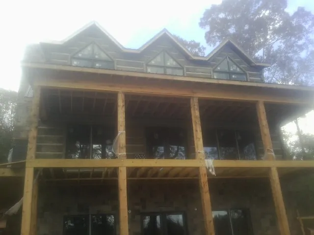 Dormers and porch framing on a large log home under construction — Roof Coating work by our crew in Harper Woods