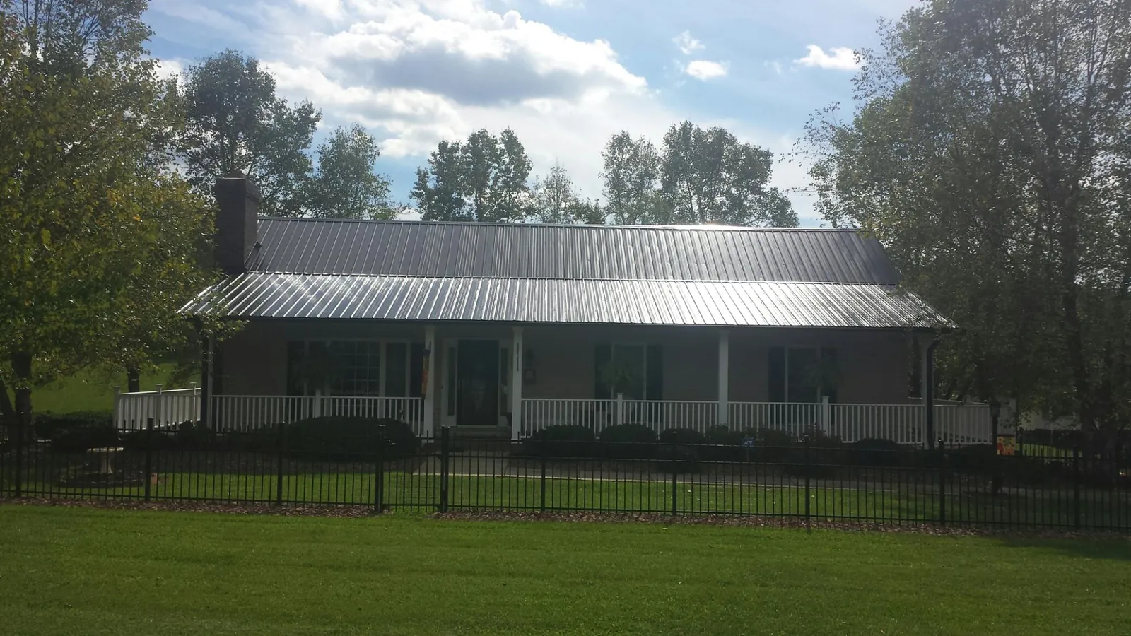 Gray metal roof on a brick ranch with a full width front porch — Gutter Guard Installation work by our crew in Harper Woods