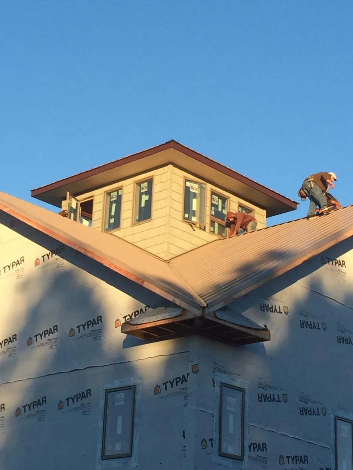 Roofers working around a rooftop cupola on a new metal roof at sunset — Roof Waterproofing in Harper Woods by Roofing Brothers